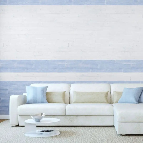 Eine dekorative Akzentwand hinter einem weißen Sofa, gestaltet mit abwechselnd weißen und hellblauen Holzpaneelen in horizontalen Streifen.