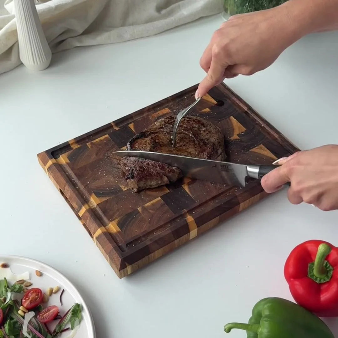 Butcherblock aus Akazie, auf dem ein Stück Fleisch geschnitten wird.
