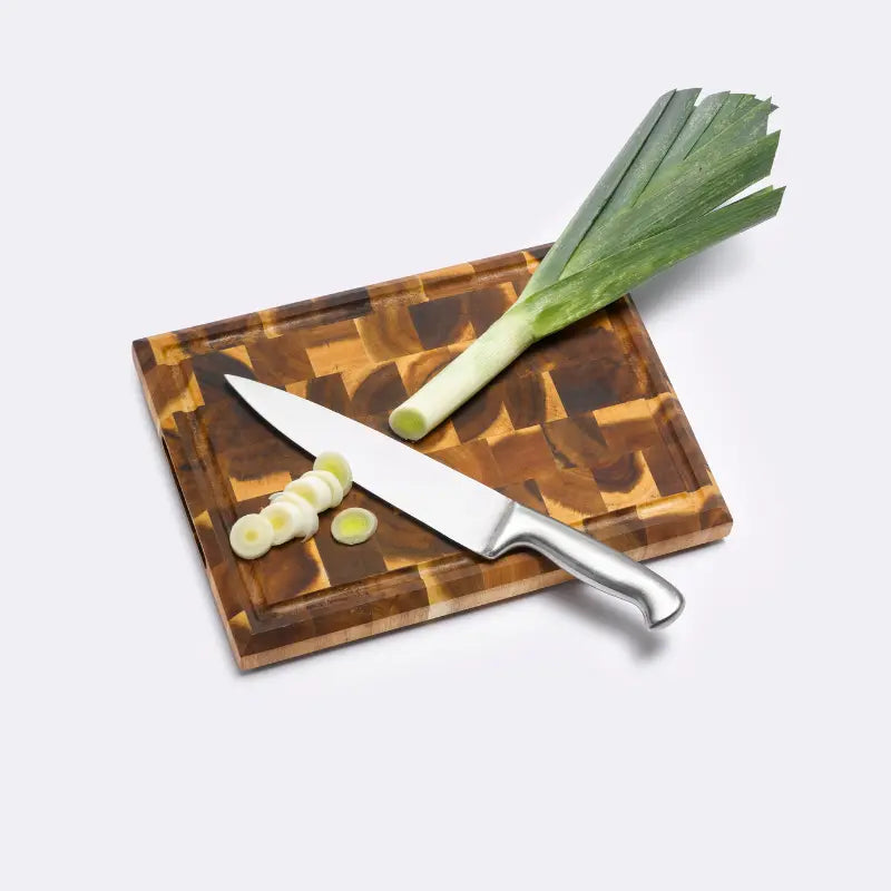 Butcherblock aus Akazienholz auf dem ein Lauch und ein Messer liegen
