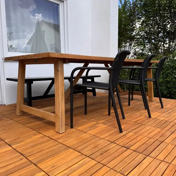 Eine mit Holzfliesen aus Akazie ausgelegte Terrasse, auf der ein Tisch mit Stühlen und einer Sitzbank steht.