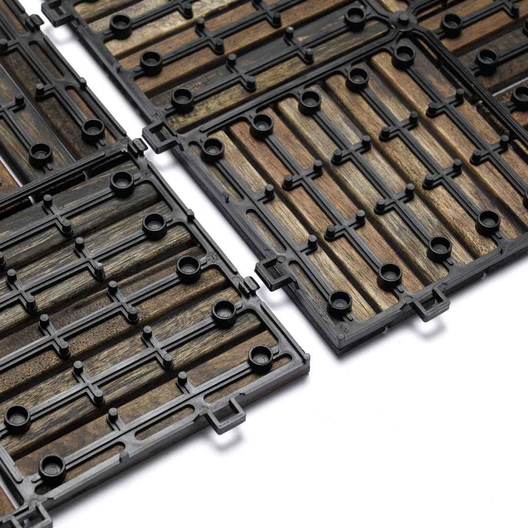 Eine Nahaufnahme der Unterseite von Holz-Klickfliesen zeigt das schwarze Kunststoff-Gitter mit integrierten Verbindungsösen. Die Konstruktion verdeutlicht das einfache Stecksystem und die Drainage-Funktion für den Außeneinsatz.