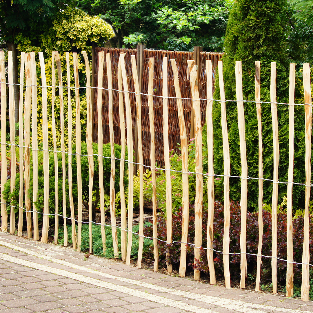 Aufnahme eines in einem Garten platzierten Staketenzauns aus Haselnussholz.