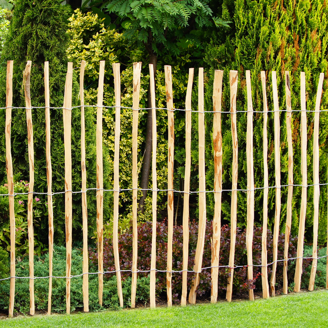 Aufnahme eines in einem Garten platzierten Staketenzauns aus Haselnussholz.