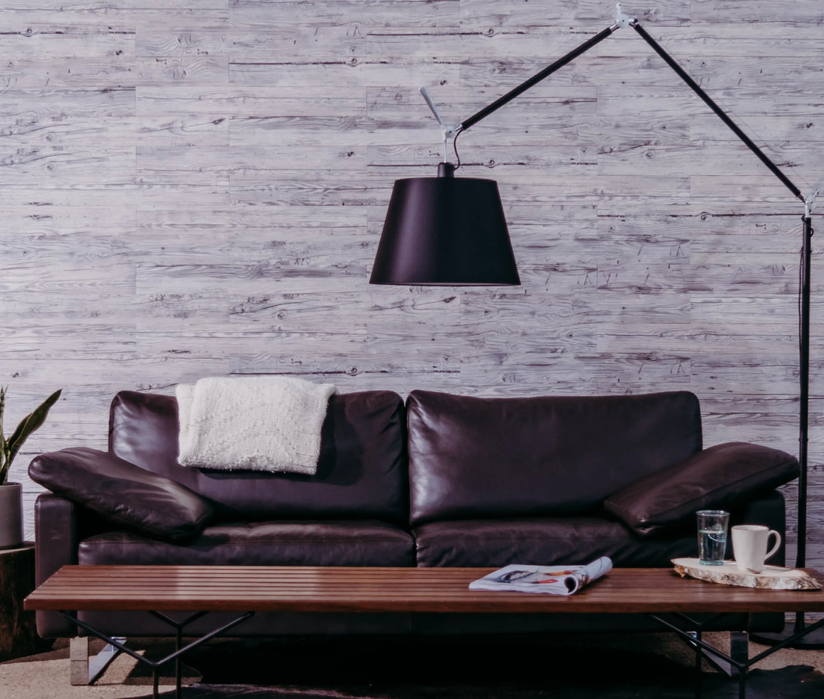 Wohnzimmerwand aus Holzpaneelen “Age” davor ein braunes Ledersofa und ein Wohnzimmertisch