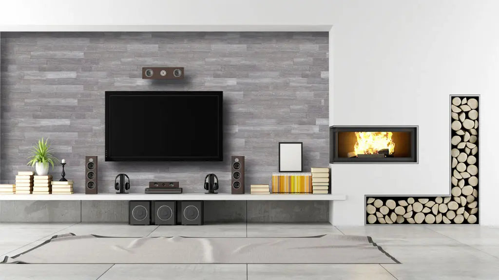 Ein moderner Wohnbereich mit einer TV-Wand in grauer Stein- oder Holzoptik. Direkt daneben ist ein flächenbündiger Kamin in die weiße Wand eingelassen, ergänzt durch ein dekoratives, L-förmiges Fach zur Lagerung von Brennholzscheiten.