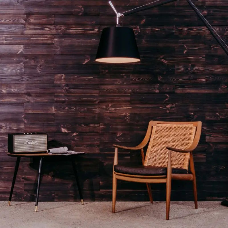 Wohnzimmerwand aus Holzpaneelen im Design „Black“, Stuhl, Lampe und Tisch davor