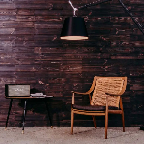 Wohnzimmerwand aus Holzpaneelen im Design „Black“, Stuhl, Lampe und Tisch davor