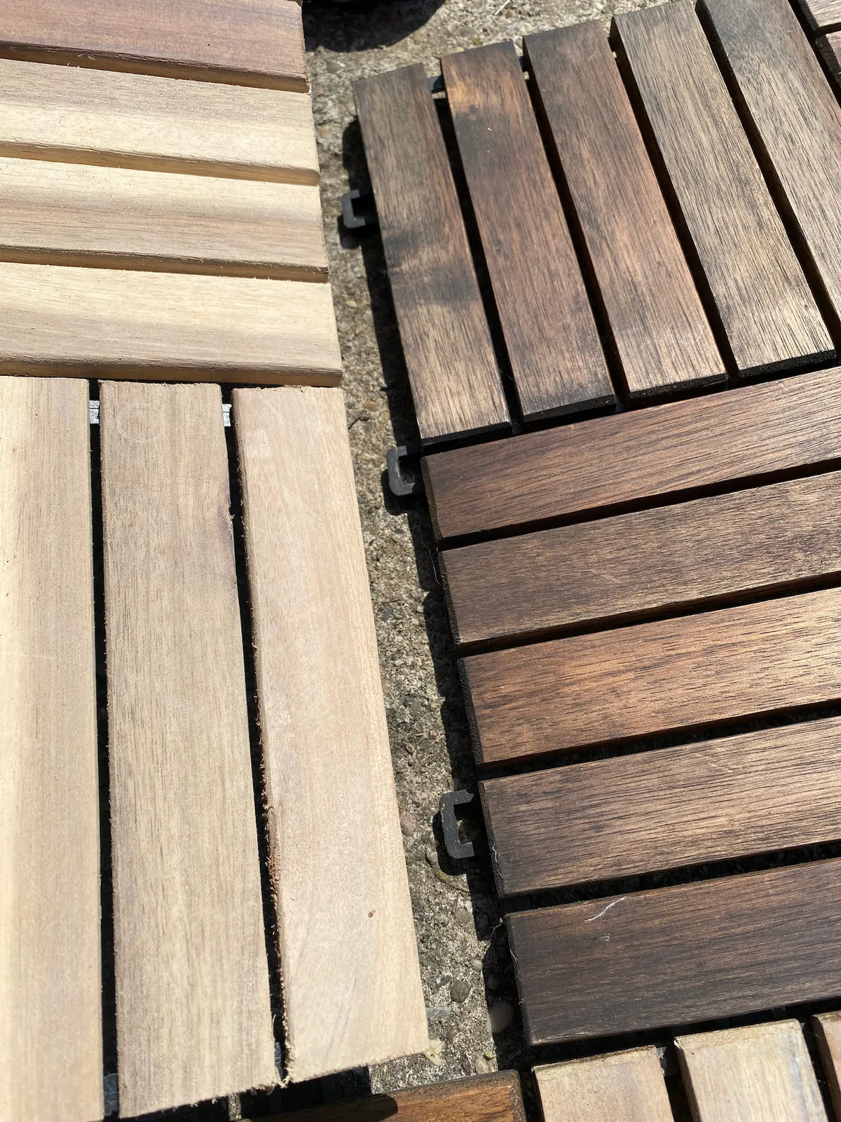 Eine Nahaufnahme zeigt den direkten Farbunterschied zwischen hellen, naturbelassenen Holz-Klickfliesen und dunkel lasierten Fliesen. Das Bild verdeutlicht die sichtbare Holzmaserung und das einfache Stecksystem an den Kanten.