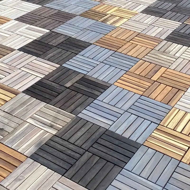 Eine großflächig verlegte Terrasse aus quadratischen Holz-Klickfliesen in verschiedenen Braun-, Grau- und Naturtönen im Schachbrettmuster.