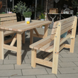 Eine rustikale Gartengarnitur aus hellem Massivholz mit einem großen Tisch und zwei passenden Sitzbänken, die mit grünen Kissen dekoriert sind. Das robuste Möbel-Set steht im Freien auf einer gepflasterten Fläche und bietet Platz für gesellige Runden.