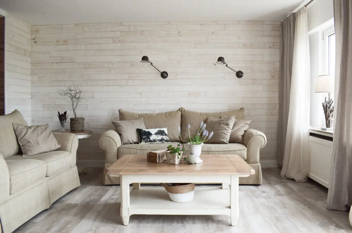 Ein helles Wohnzimmer mit zwei Sofas und einem Holztisch vor einer Wand aus Holzpaneelen