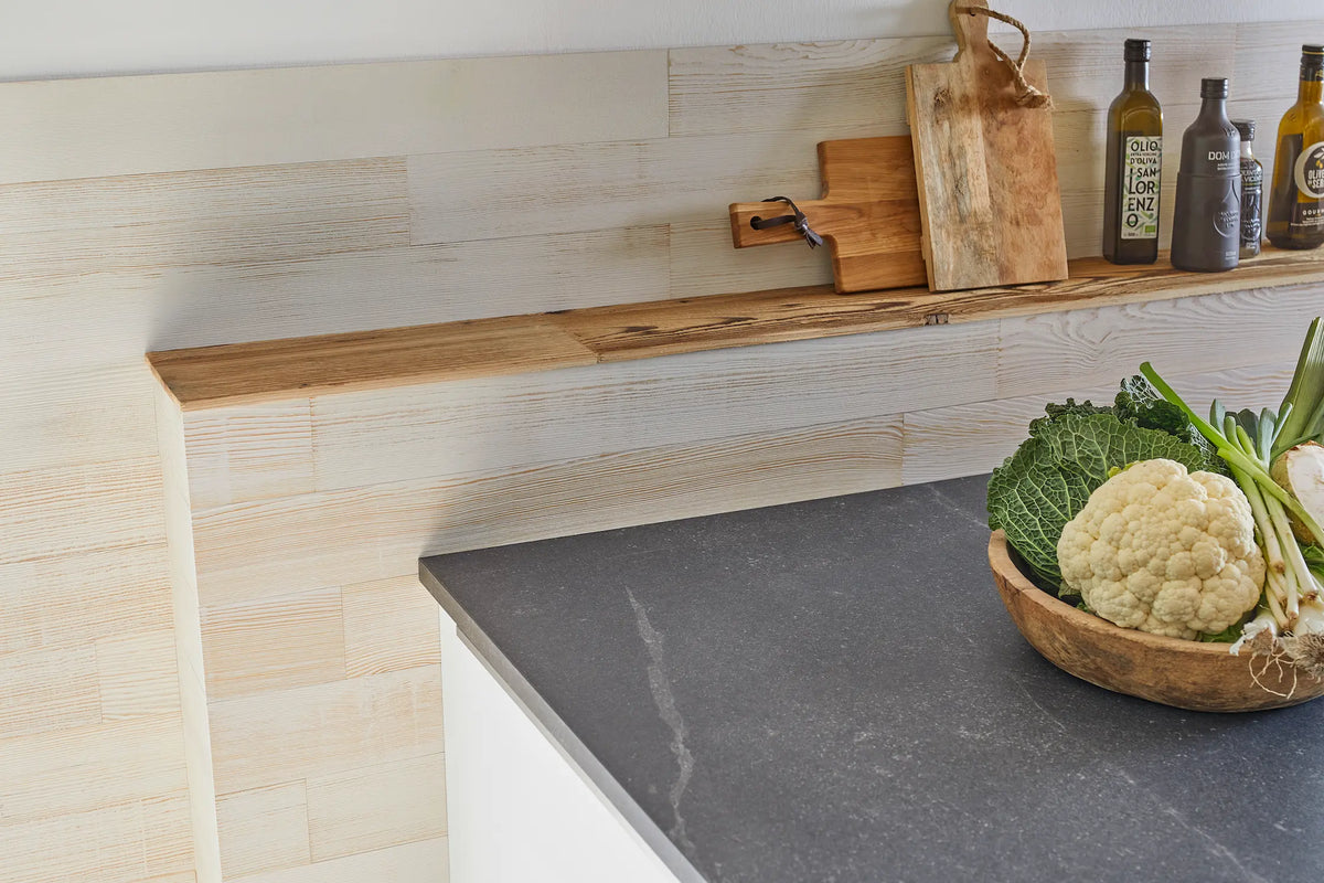 Nahaufnahme der Küchenwand aus Holzpaneelen “White” und Gemüsekorb auf Theke