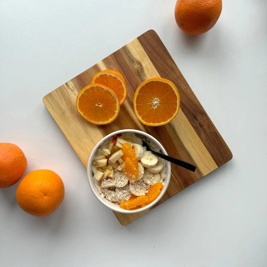 Schneidebrett aus Akazienholz dekoriert mit einer Schüssel Joghurt mit Früchten